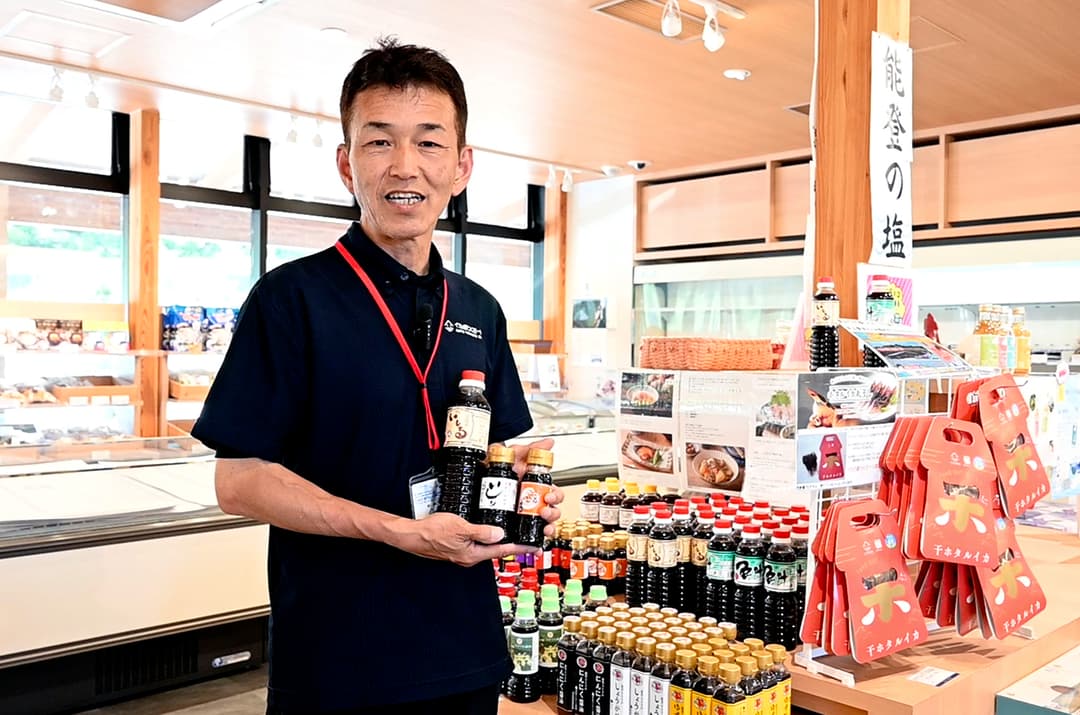 “イカの駅 つくモール”の駅長・吉村昌央さん。手にしているのは特産のイカで作った魚醤「イシリ」